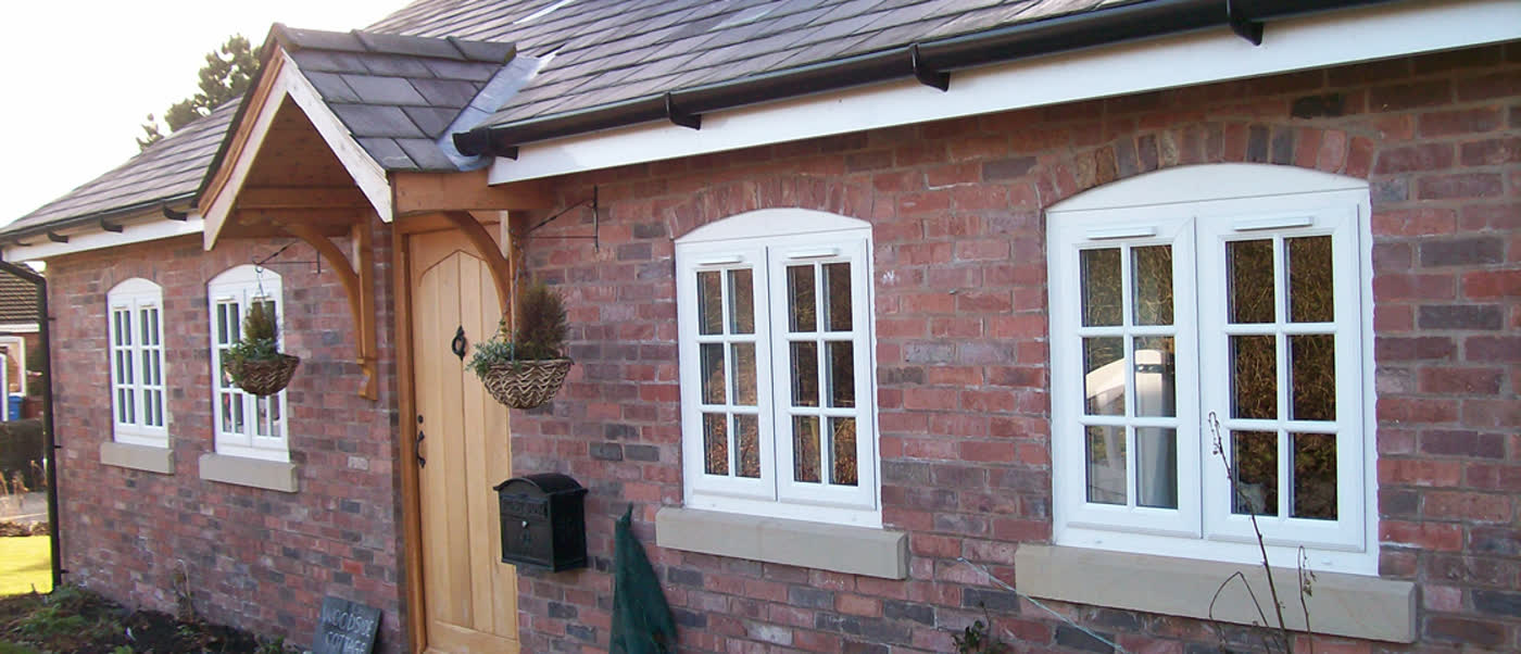 Red-brick cottage front with lattice windows, timber door and a gabled porch