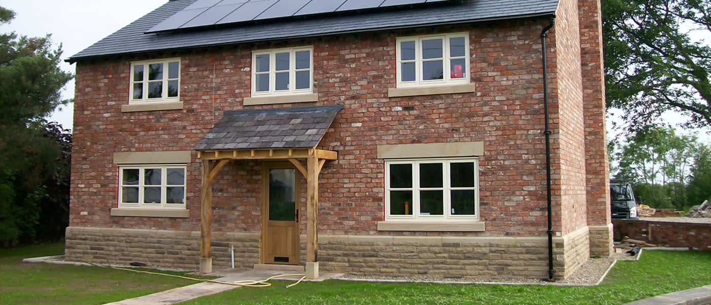 Finished two-storey brick house with a timber porch, cream windows and solar panels