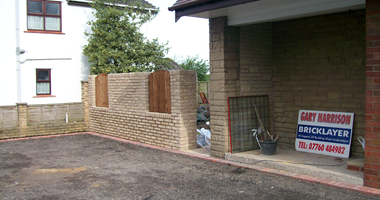 Gary Harrison Bricklayer site sign beside new stonework and a prepared drive
